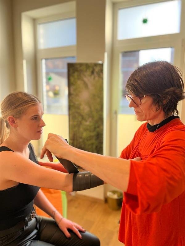Andrea Heumann behandelt den Arm einer Patientin mit einem Flossing-Band