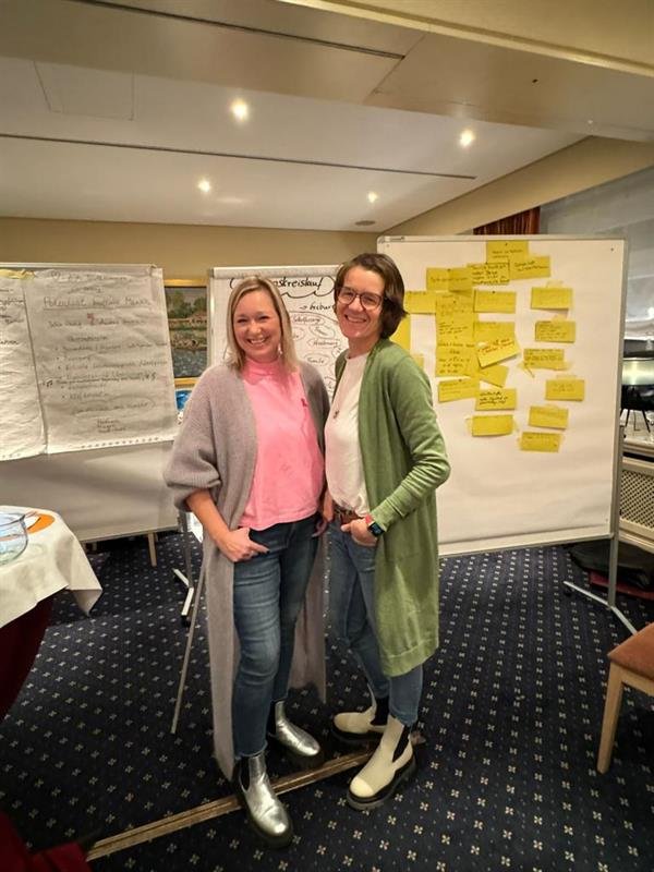 Andrea Heumann mit einer Teilnehmerin bei einem Workshop vor einer Pinnwand